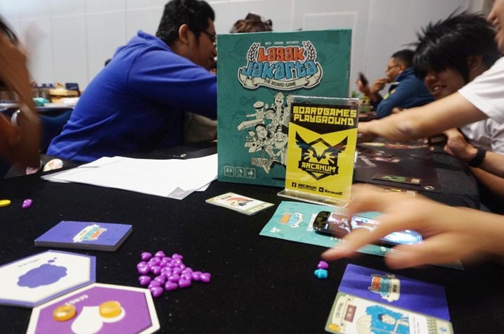 Salah satu booth di Jakarta Comic Con 2015 yang unik adalah Boardgames Playground yaitu komunitas pecinta boardgames yang menciptakan boardgames asli Indonesia “Lagak Jakarta” dan “Santet”. Mereka mengajak para pengunjung untuk bermain bersama.