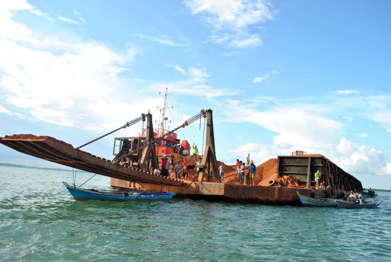 Kapal tongkang berisi biji bauksit yang siap ekspor di perairan Senggarang, Tanjungpinang. (Foto: Antara)