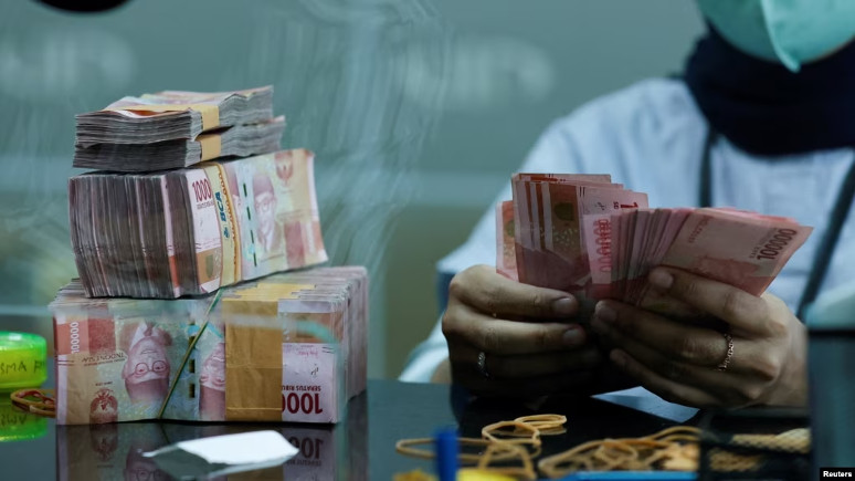 ILUSTRASI - Seorang teller menghitung lembaran uang kertas rupiah di tempat penukaran mata uang asing di Jakarta, 14 Oktober 2022. (REUTERS/Willy Kurniawan).