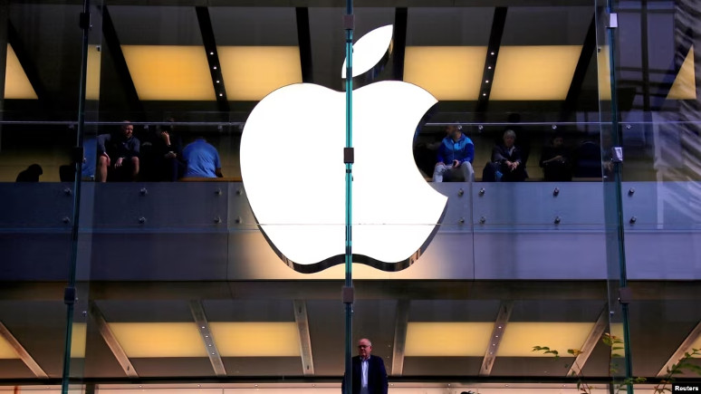 Seorang pelanggan berdiri di bawah logo Apple yang menyala saat dia melihat ke luar jendela toko Apple yang terletak di pusat kota Sydney. (Foto: Reuters)