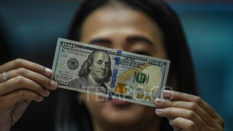 Seorang karyawan tengah mengamati uang pecahan 100 dolar Amerika di penukaran valuta asing di Jakarta. Tempo/Tony Hartawan